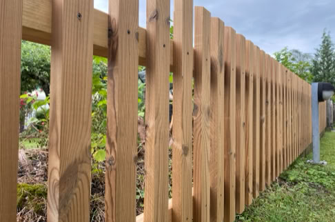 FHG am Hörnli, Holzzaun auf einer Wiese mit Bäumen im Hintergrund.