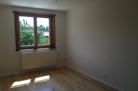 FHG am Hörnli, Leerer Raum mit Holzboden, einem Fenster mit Holzrahmen und einem Heizkörper darunter.