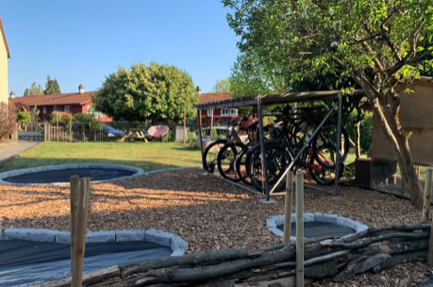 FHG am Hörnli, Fahrradständer mit mehreren Fahrrädern, umgeben von Bäumen und Rasen, im Hintergrund Wohnhäuser.