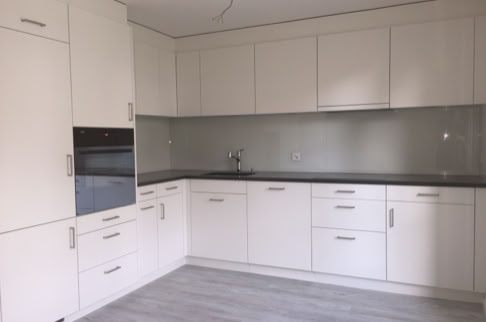 FHG am Hörnli, Moderne Küche mit weißen Schränken, grauer Arbeitsplatte und eingebautem Ofen.