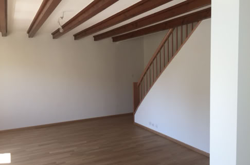 FHG am Hörnli, Leerer Raum mit Holzboden, weißen Wänden und sichtbaren Holzbalken an der Decke. Eine Holztreppe führt nach oben.